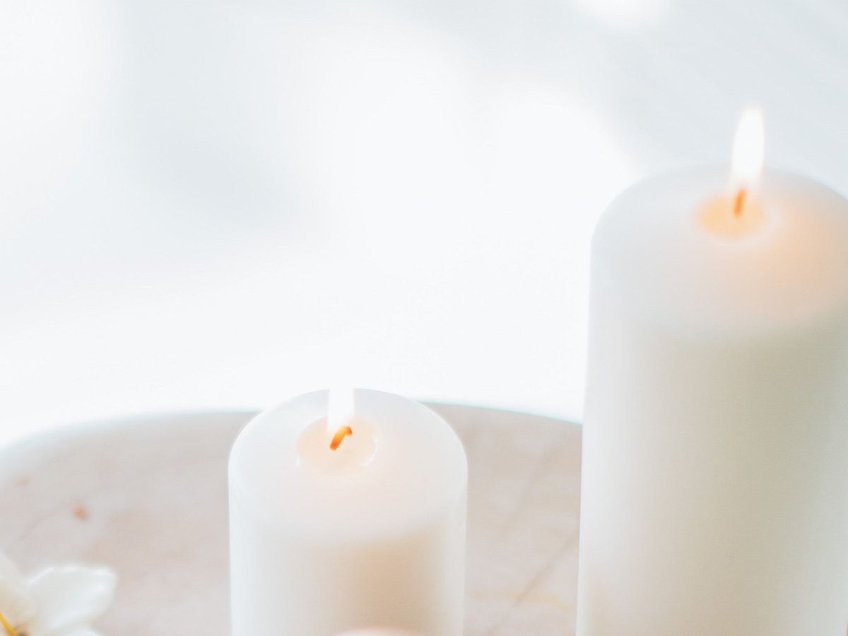 Two lit candles on a wooden stool