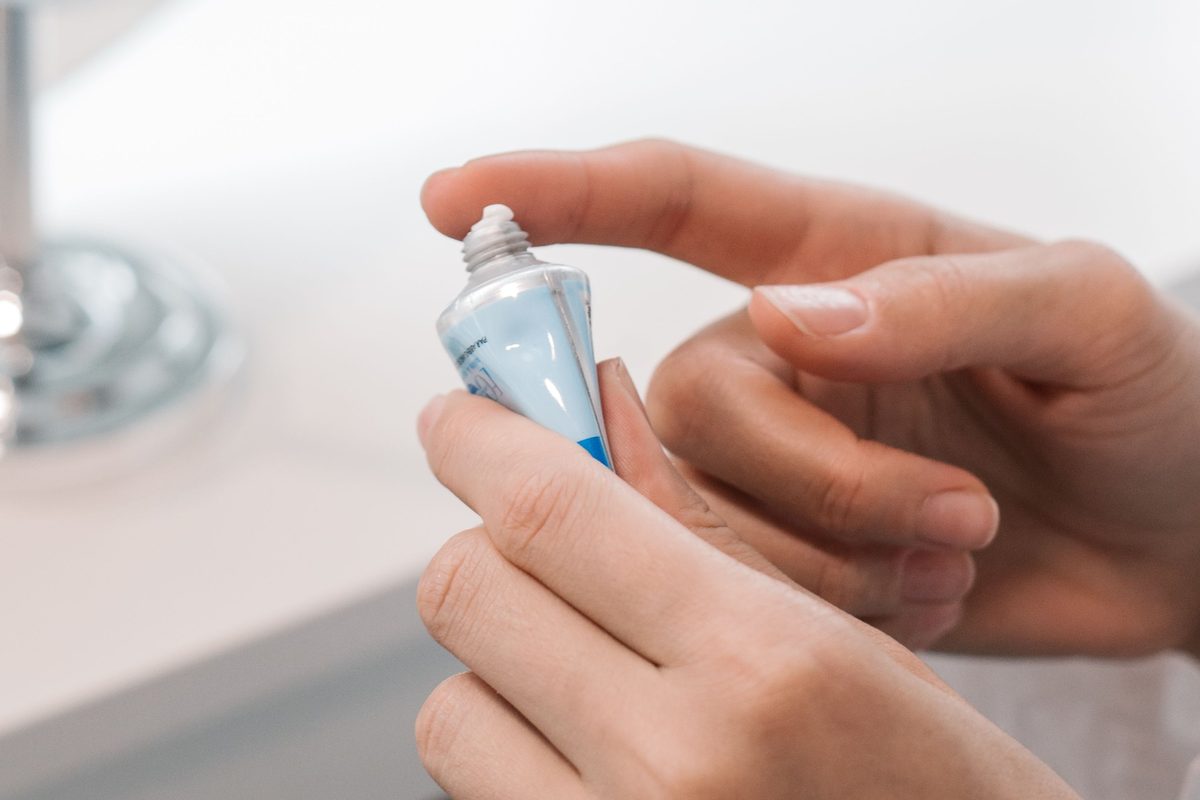Hands squeezing moisturizer from a tube, the daily step after dermaplaning