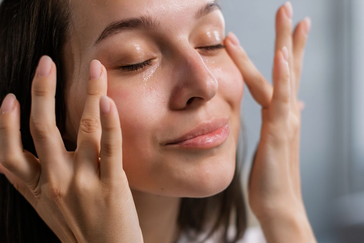 A woman pressing serum gently into her cheeks with her fingertips