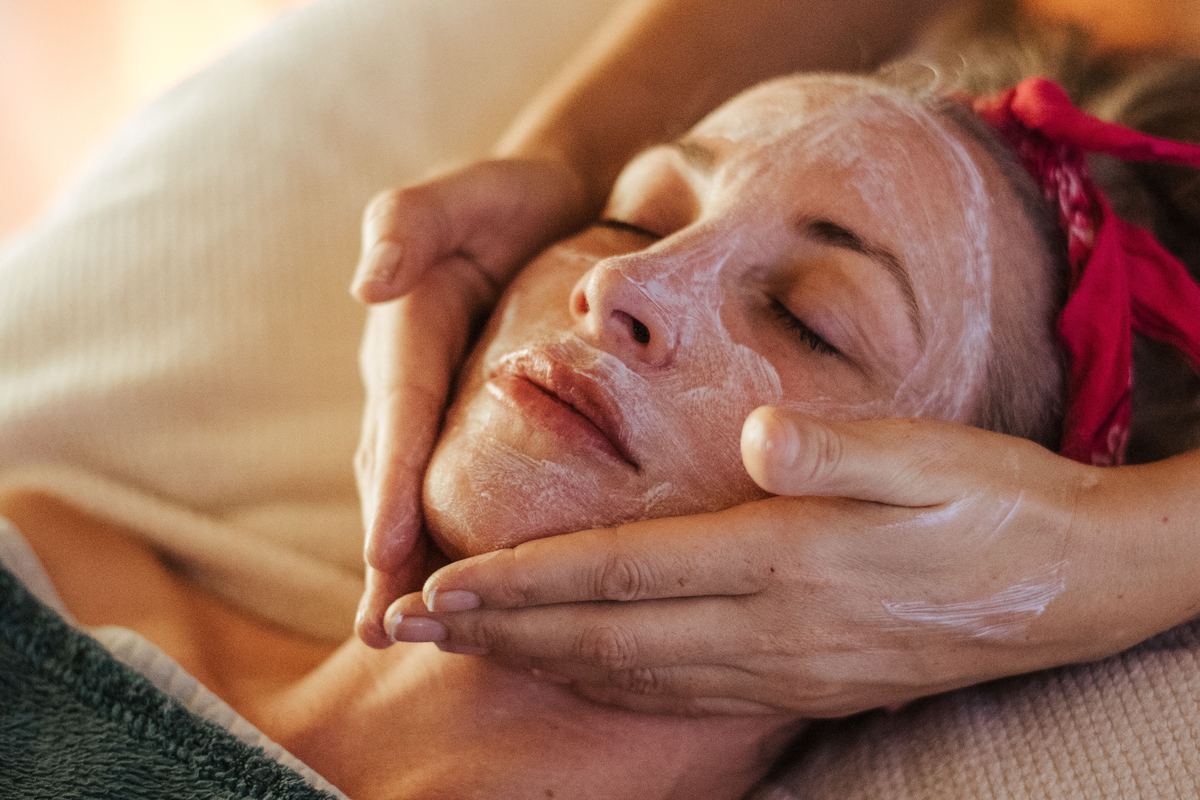 An esthetician working a treatment into a client’s face by hand