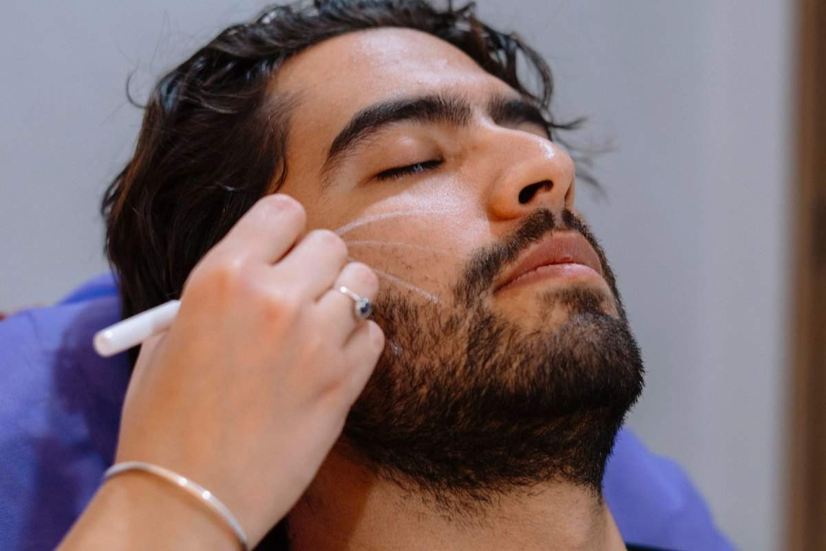 A man resting with his eyes closed while a small tool works along his cheek and jaw
