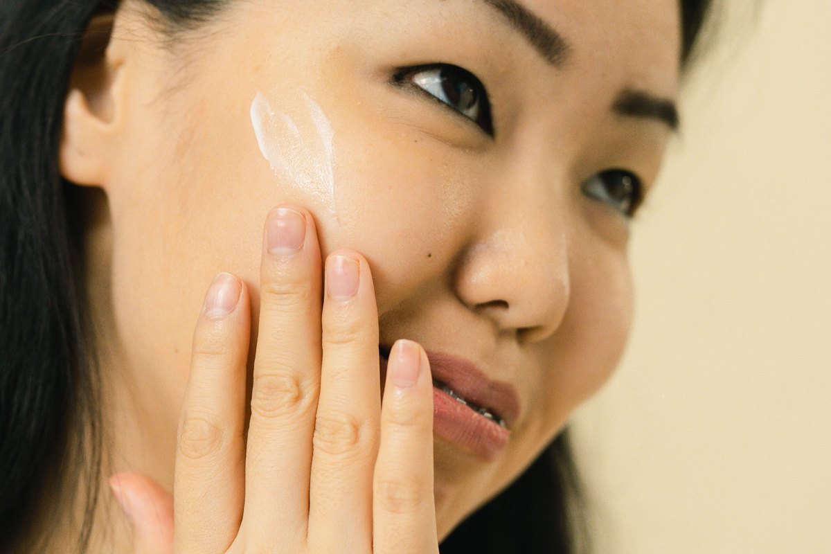 A woman pressing a light layer of balm into her cheek with her fingertips
